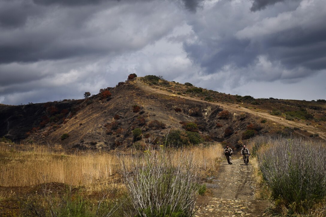 Marines walk down mountainous terrain during the 2015 Recon Challenge at Camp Pendleton, California, May 15, 2015. This 30-mile gauntlet tests Marines and sailors' physical and mental strength during exercises such as finning, live fire, and pool events. Competetors carry flags of the names of fallen Recon Marines to keep their memory alive. (U.S. Marine Corps photo by Sgt. Ally Beiswanger/Released)