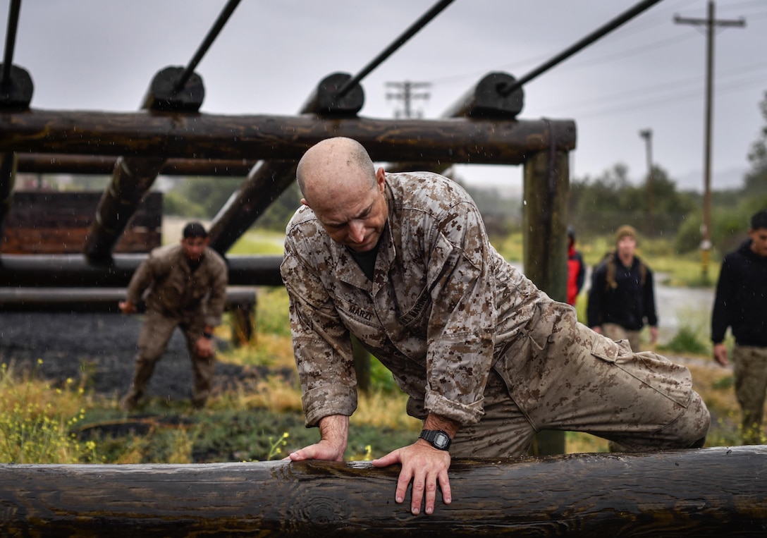 Master Sgt. Vincent Marzi climbs through the O-Course during the 2015 Recon Challenge aboard Camp Pendleton, California, May 15, 2015. This 30-mile gauntlet tests Marines and sailors' physical and mental strength during exercises such as finning, live fire, and pool events. Competitors carry flags of the names of fallen Recon Marines to keep their memory alive. 