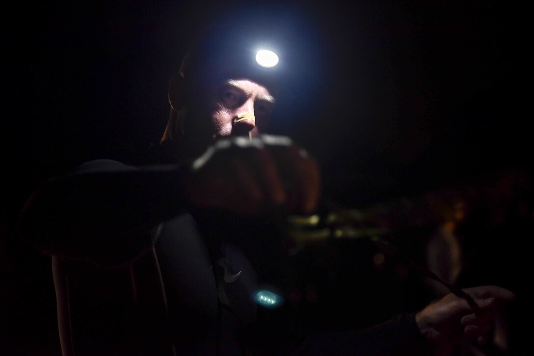 A Marine prepares his gear before finning through the Pacific Ocean at 4:00 a.m. during the 2015 Recon Challenge. This 30-mile gauntlet tests Marines' physical and mental strength during exercises such as finning, live fire, and pool events. Competetors carry flags of the names of fallen Recon Marines to keep their memory alive. (U.S. Marine Corps photo by Sgt. Ally Beiswanger/Released)