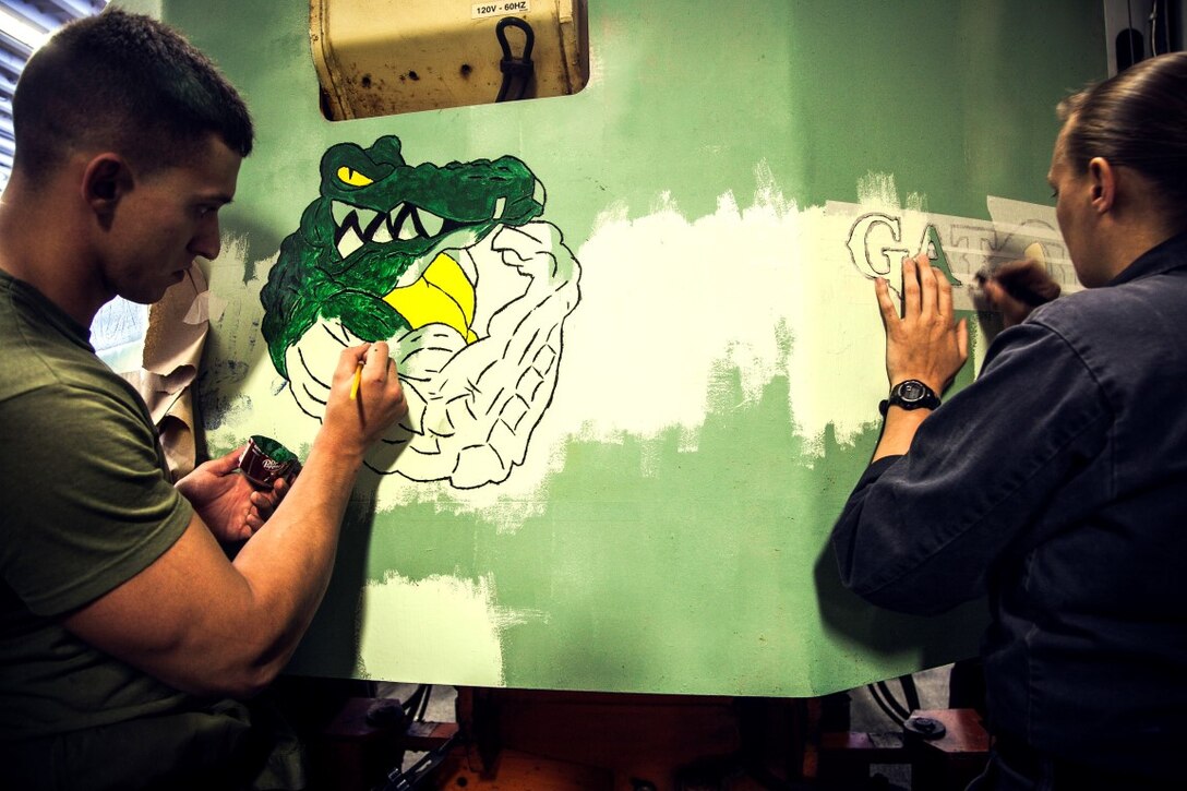 U.S. Marine Cpl. Zachary Maples and Navy Aviation Support Equipment Technician Airman Christine Lachico, paint a new logo on equipment in the hangar bay of the USS Essex (LDH 2) at sea in the Pacific Ocean, May 16, 2015. Both Maples and Lachico are part of aviation ground support equipment element with the 15th Marine Expeditionary Unit and the Essex Amphibious Ready Group, embarked on a seven-month deployment.  (U.S. Marine Corps photo by Cpl. Elize McKelvey/Released)