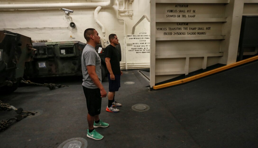 U.S. Marines Cpl. Jose Martinez, left, and Sgt. Ramon Rodriguez prepare to run sprints up a ramp in the well deck of the USS Anchorage (LPD-23) at sea in the Pacific Ocean, May 13, 2015. Martinez is an administrative specialist, and Rodriguez is a motor transportation operator, both with Combat Logistics Battalion 15, 15th Marine Expeditionary Unit. Marines find creative ways to stay fit while aboard ship. (U.S. Marine Corps photo by Cpl. Steve H. Lopez/Released)