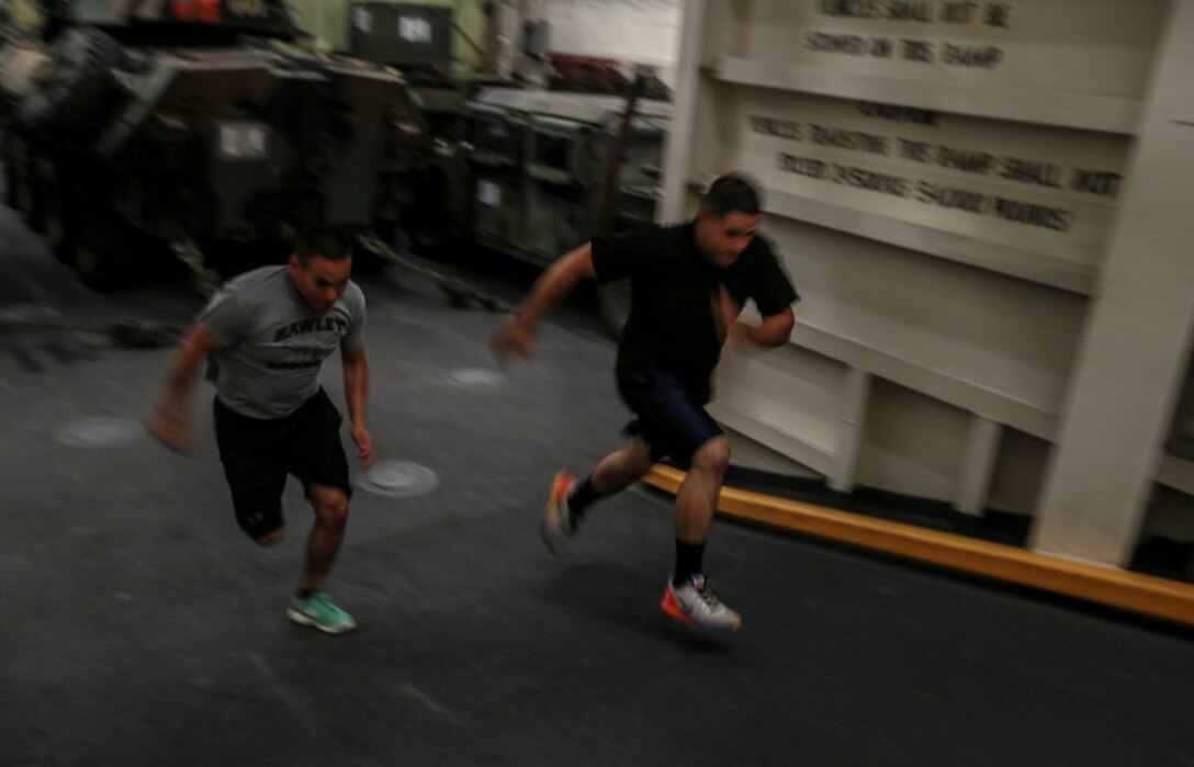 U.S. Marines Cpl. Jose Martinez, left, and Sgt. Ramon Rodriguez sprint up a ramp in the well deck of the USS Anchorage (LPD-23) at sea in the Pacific Ocean, May 13, 2015. Martinez is an administrative specialist, and Rodriguez is a motor transportation operator both with Combat Logistics Battalion 15, 15th Marine Expeditionary Unit. Marines find creative ways to stay fit while aboard ship. (U.S. Marine Corps photo by Cpl. Steve H. Lopez/Released)