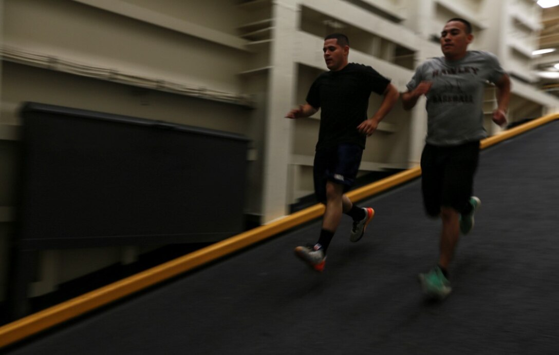 U.S. Marines Cpl. Jose Martinez, right, and Sgt. Ramon Rodriguez sprint down a ramp in the well deck of the USS Anchorage (LPD-23) at sea in the Pacific Ocean, May 13, 2015. Martinez is an administrative specialist, and Rodriguez is a motor transportation operator both with Combat Logistics Battalion 15, 15th Marine Expeditionary Unit. Marines find creative ways to stay fit while aboard ship. (U.S. Marine Corps photo by Cpl. Steve H. Lopez/Released)