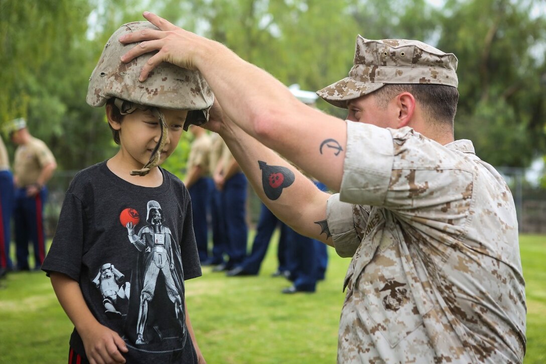 Jackson, Ohio native, Cpl. Joshua Sikich, a fire supportman with the 11th Marine Expeditionary Unit, I Marine Expeditionary Force, places his Kevlar helmet on a child during a display of capabilities prior to the first annual 11th MEU adoption ceremony in the city of Yorba Linda, Calif. May 16, 2015. The adoption represents the constant support provided to the troops and their families when the unit is deployed and at home, and maintains a constant link between Yorba Linda and the military community. The 11the MEU is a flexible, adaptable, and persistent force capable of rapidly responding to crises and contingencies. (U.S. Marine Corps photos by Cpl. Rick Hurtado/Released)