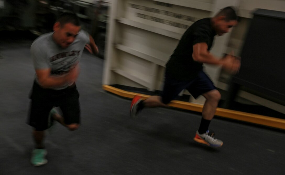 U.S. Marines Cpl. Jose Martinez, left/right, and Sgt. Ramon Rodriguez sprint up a ramp in the well deck of the USS Anchorage (LPD-23) at sea in the Pacific Ocean, May 13, 2015. Martinez is an administrative specialist, and Rodriguez is a motor transportation operator both with Combat Logistics Battalion 15, 15th Marine Expeditionary Unit. The Marines of the 15th MEU make sure to practice the physical mission even while deployed. (U.S. Marine Corps photo by Cpl. Steve H. Lopez/Released)
