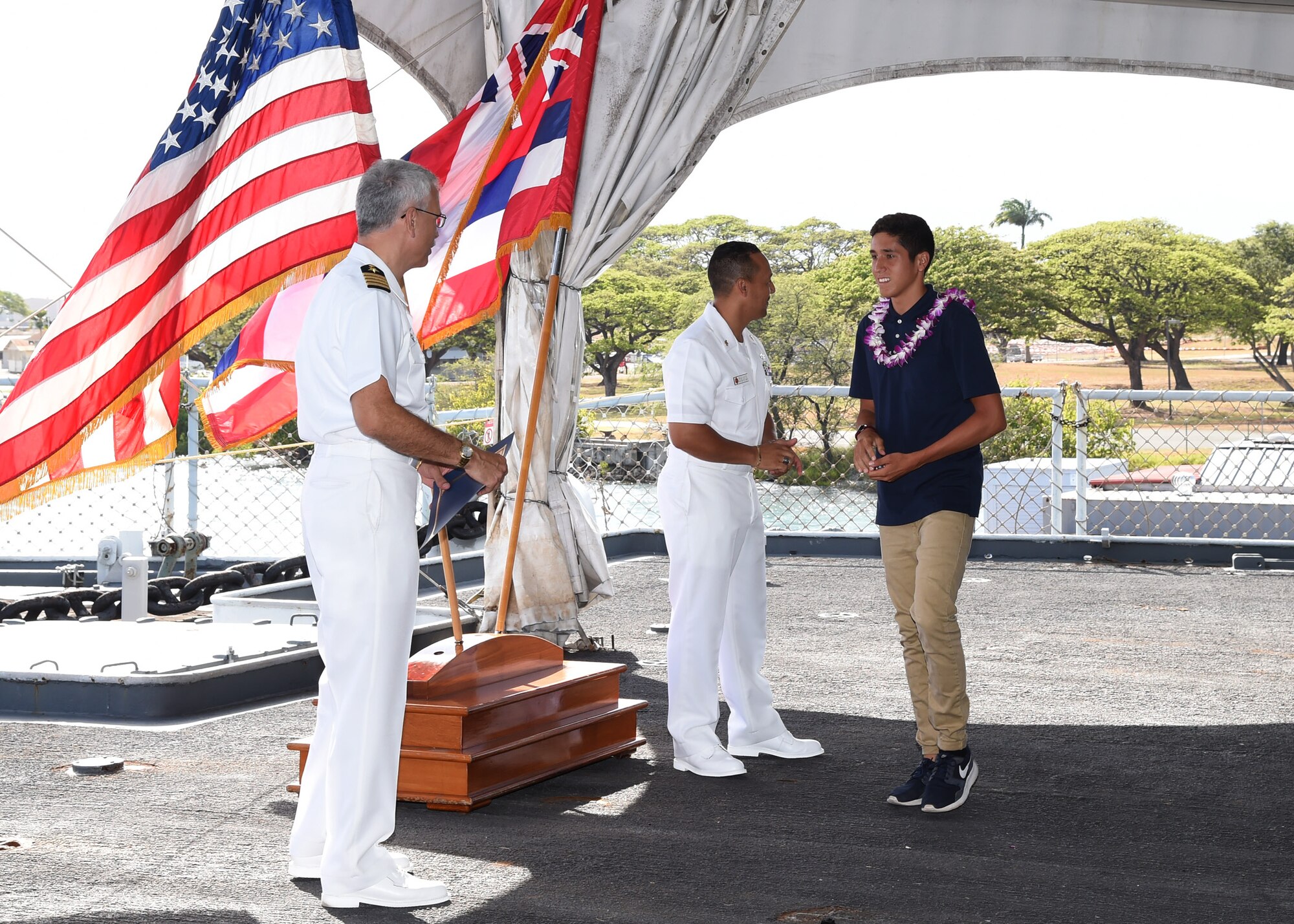 A U.S. Navy enlistee and high school graduate is recognized by Senior chief Petty Officer Enrique Acosta, senior enlisted leader Joint Typhoon Warning Center, and Capt. Ashley Evans, commanding officer of JTWC, during the Our Community Salutes Recognition Ceremony at the USS Battleship Missouri Memorial on Ford Island, Hawaii, May 17, 2015. Our Community Salutes is a community-based initiative to recognize and honor graduating high school seniors who plan to join the Armed Forces after graduation. The OCS ceremony started in southern New Jersey in 2009 and has now spread across the nation.  (U.S. Air Force photo by Tech. Sgt. Aaron Oelrich/Released) 