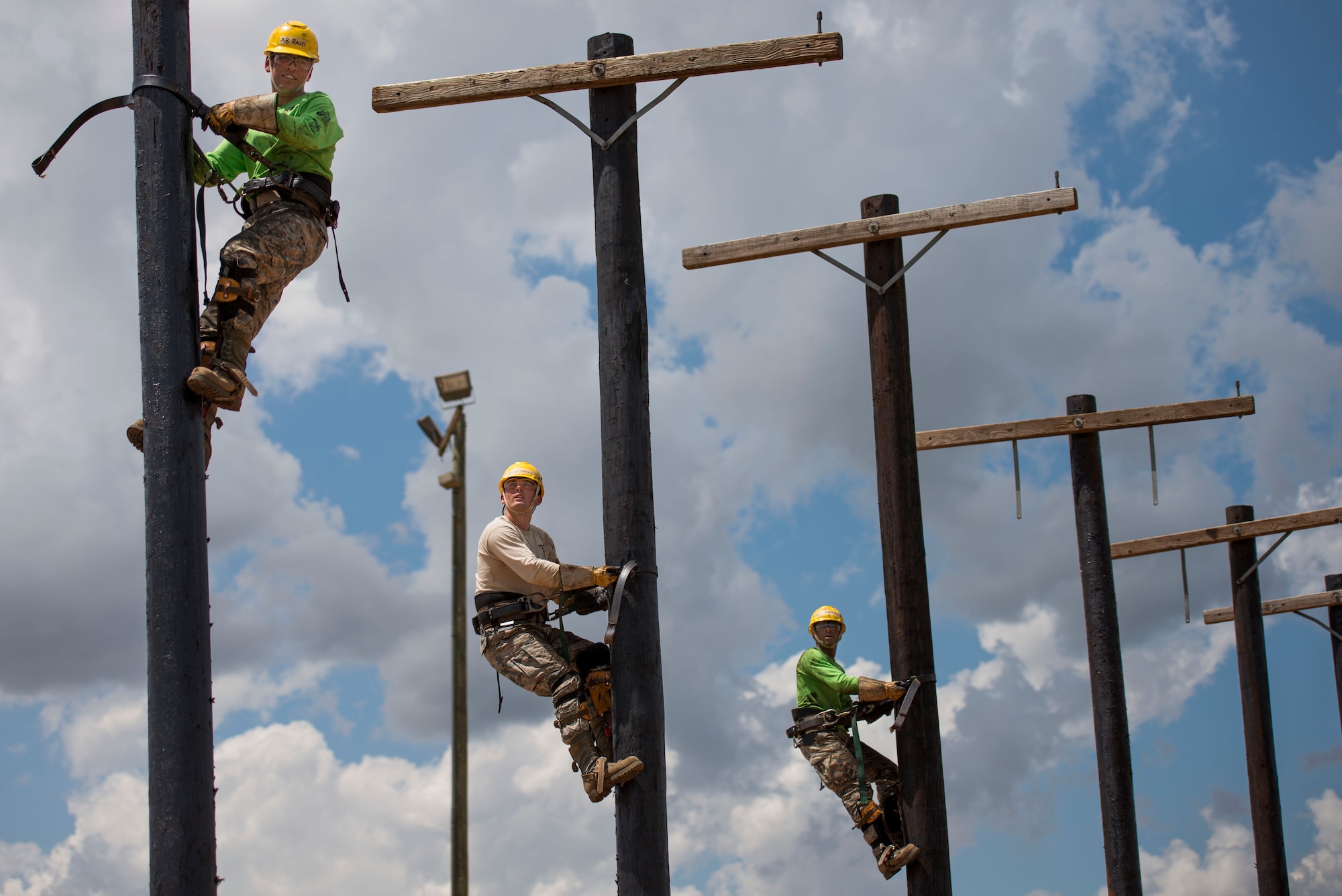 U.S. Air Force Airmen climb utility poles during their training at Sheppard Air Force Base, Texas, May 18, 2015. This part of their training teaches students how to safely and effectively climb utility poles so they may work on necessary electrical systems. (U.S. Air Force photo by Senior Airman Kyle Gese/Released)