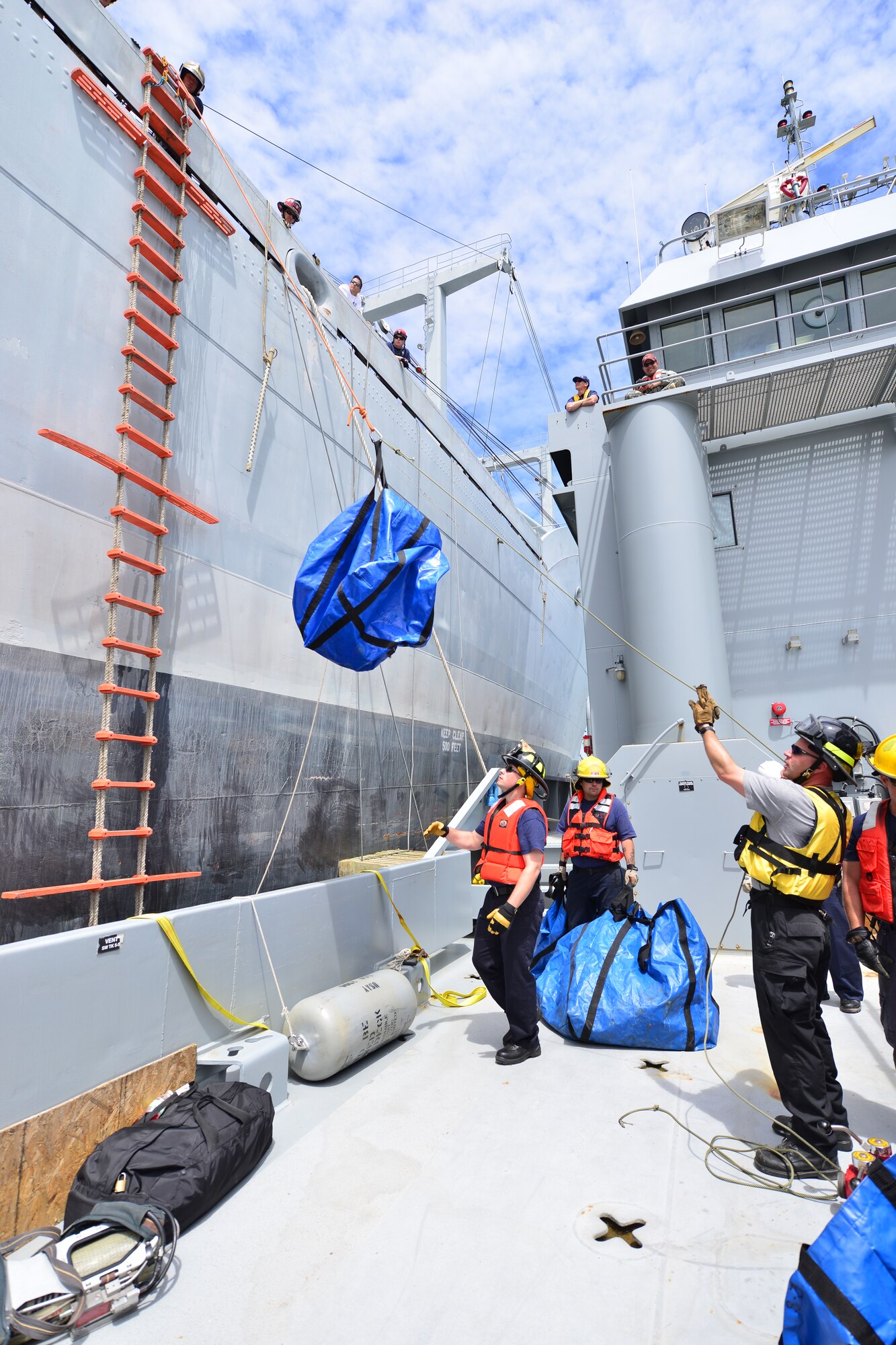 Hampton Roads Marine Firefighting School students hoist equipment to a National Defense Reserve vessel during a maritime incident response exercise at Fort Eustis, Va., May 15, 2015. After transferring equipment to the vessel, the students went through a simulated fire exercise in which they rescued two people from different locations within the ship. (U.S. Air Force photo by Staff Sgt. Natasha Stannard/Released)