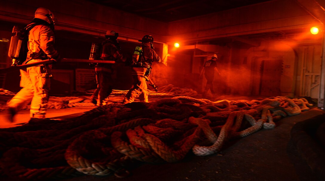 Hampton Roads Marine Firefighting School students enter a simulated fire aboard a National Defense Reserve vessel during the 24th Annual Hampton Roads Marine Firefighting School maritime incident response exercise at Fort Eustis, Va., May 15, 2015. The exercise was the capstone event for the school, testing all the students learned about responding to a maritime fire incident. (U.S. Air Force photo by Staff Sgt. Natasha Stannard/Released) 