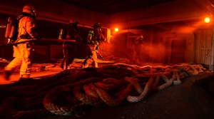 Hampton Roads Marine Firefighting School students enter a simulated fire aboard a National Defense Reserve vessel during the 24th Annual Hampton Roads Marine Firefighting School maritime incident response exercise at Fort Eustis, Va., May 15, 2015. The exercise was the capstone event for the school, testing all the students learned about responding to a maritime fire incident. (U.S. Air Force photo by Staff Sgt. Natasha Stannard/Released) 