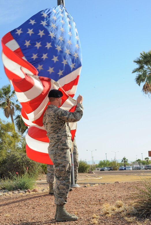 U.S. Air Force Staff Sgt. Collin Coldwell, 355th Security Forces Squadron flag detail NCO-in-charge, secures the American flag during a retreat ceremony for National Police Week at Davis-Monthan Air Force Base, Ariz., May 14, 2015. A retreat ceremony is a military tradition that serves two purposes: to signal the end of the official duty day and serve as a ceremony to pay respect to the American flag. (U.S. Air Force photo by Staff Sgt. Angela Ruiz/released)
