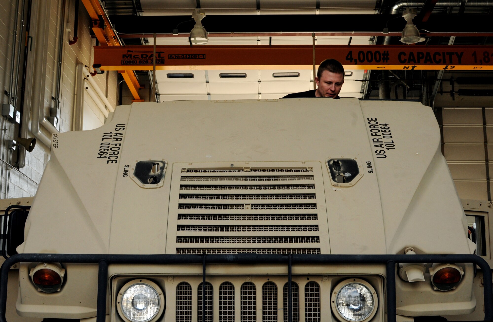A picture of U.S. Air Force Senior Airman Skylar Marine, a member of the 227th Air Support Operations Squadron, lifting the hood of a High Mobility Multipurpose Wheeled Vehicle.