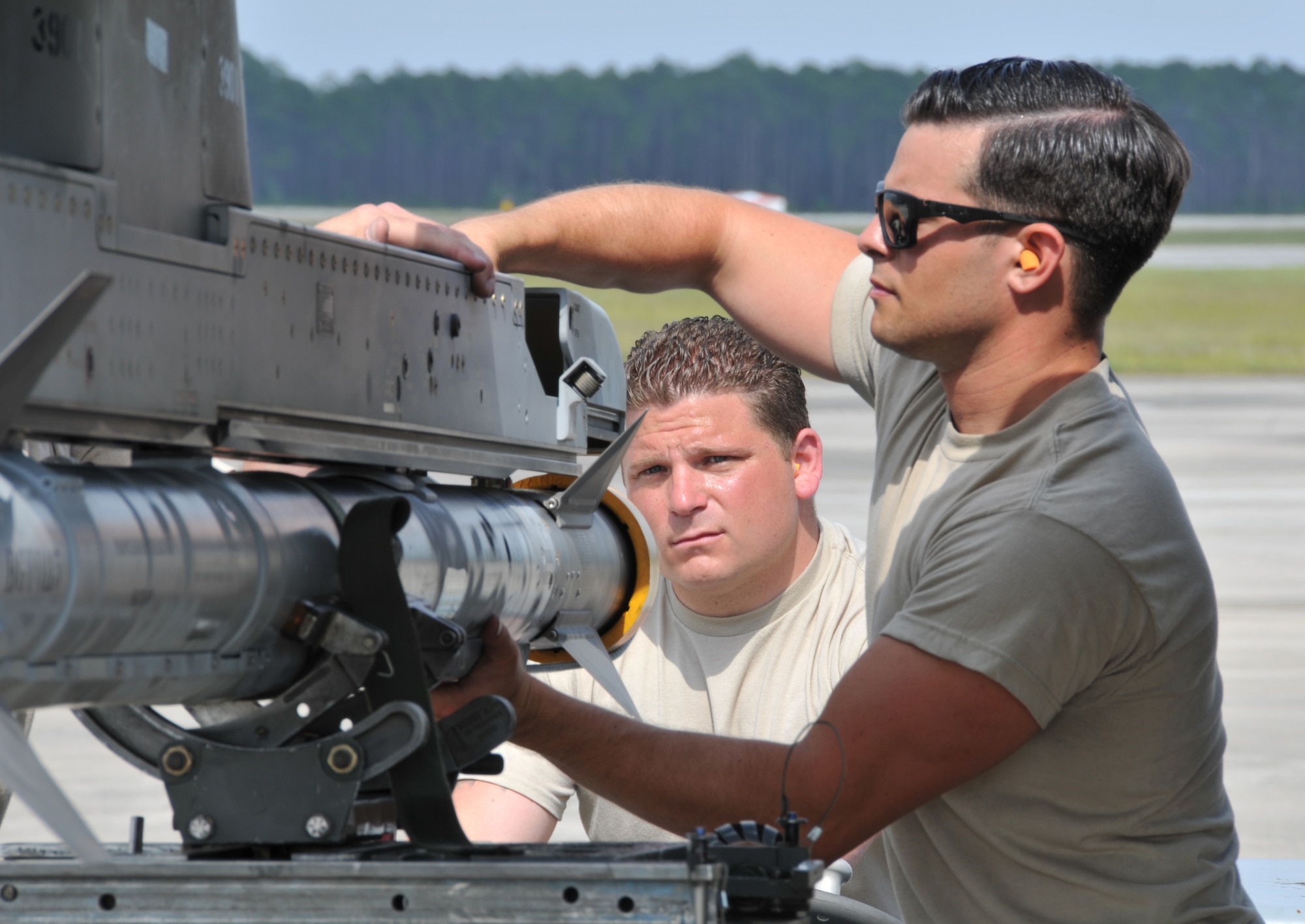 A picture of U.S. Air Force Senior Airman Vince Avallone and Tech. Sgt. Nicholas Celentano, weapons loaders with the 177th Fighter Wing of the New Jersey Air National Guard, loading an AIM-9X pracice missile onto an F-16 Fighting Falcon.