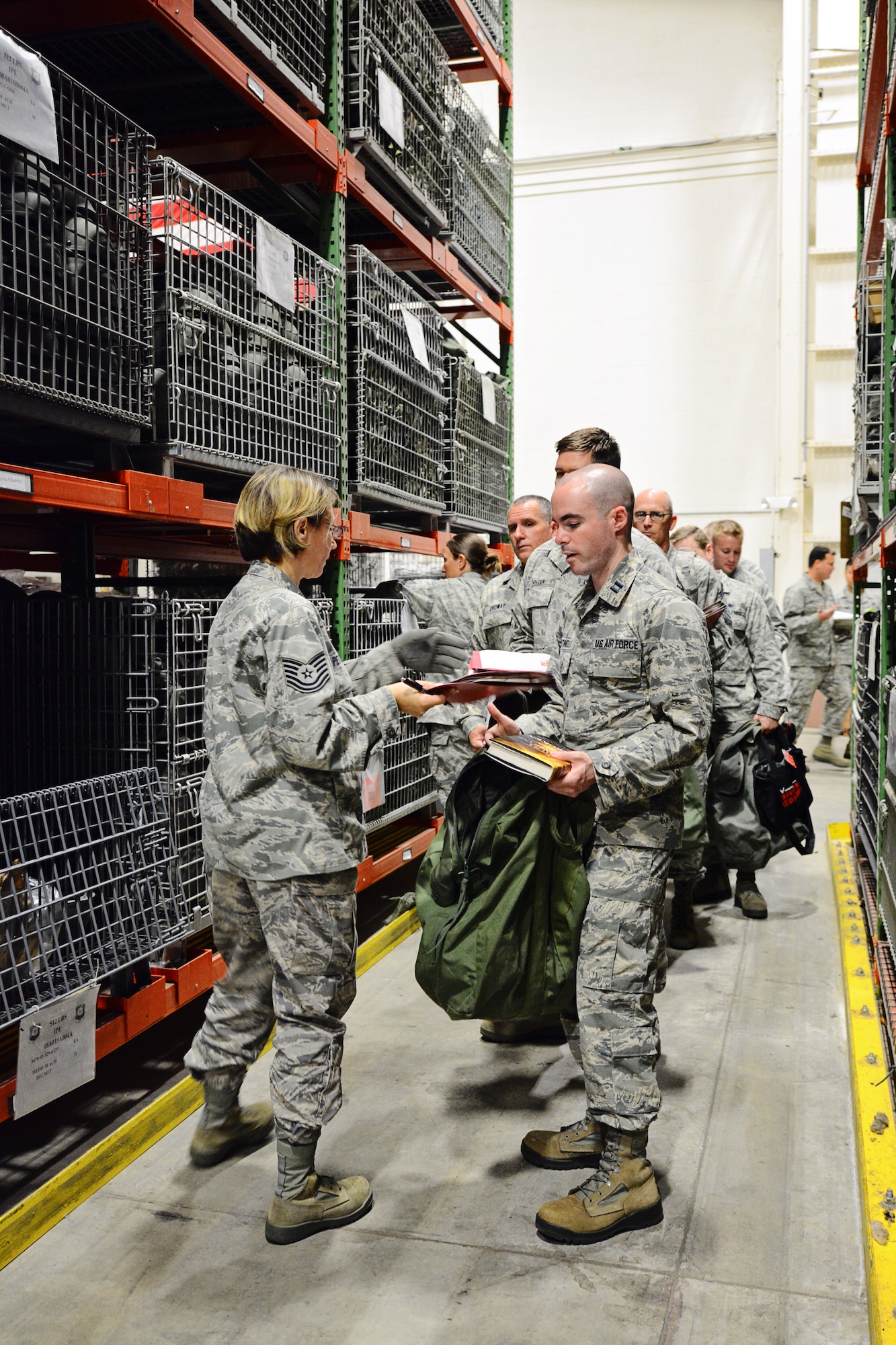 Tech. Sgt. Mary Peterson, 512th Logistical Readiness Squadron, issues helmets to simulated deploying members during a mass deployment exercise May 17, 2015, at Dover Air Force Base, Del. More than 60 reservists simulated activation, including deployment processing lines and a "bag drag" of all their combat equipment. (U.S. Air Force Photo/Staff Sgt. Mercedes Crossland)