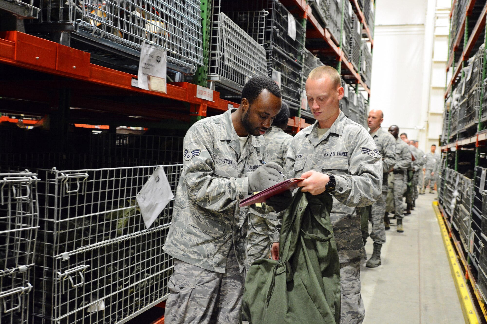 Senior Airman Pernelle Tyler (left), 512th Logistics Readiness Center, signs an accountability form for a canteen cover and web belt issued to Senior Airman Jeremy Dvorak’s, 46th Aerial Port Squadron, during a deployment exercise May 17, 2015, at Dover Air Force Base, Del. More than 60 reservists simulated activation, including deployment processing lines and a "bag drag" of all their combat equipment. (U.S. Air Force Photo/Staff Sgt. Mercedes Crossland)