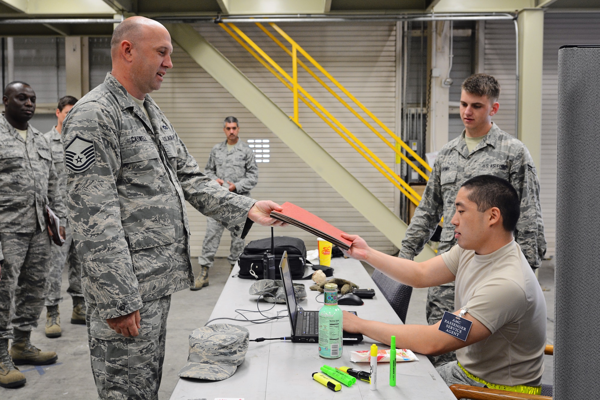 Master Sgt.  Jeffery Caswell (left), 46th Aerial Port Squadron, gives his mobility folder to Senior Airman Jacob Croegaert, 436th Aerial Port Squadron, during a deployment exercise to rehearse a mass deployment situation May 17, 2015, at Dover Air Force Base, Del. More than 60 reservists simulated activation, including deployment processing lines and a "bag drag" of all their combat equipment. (U.S. Air Force Photo/Staff Sgt. Mercedes Crossland)