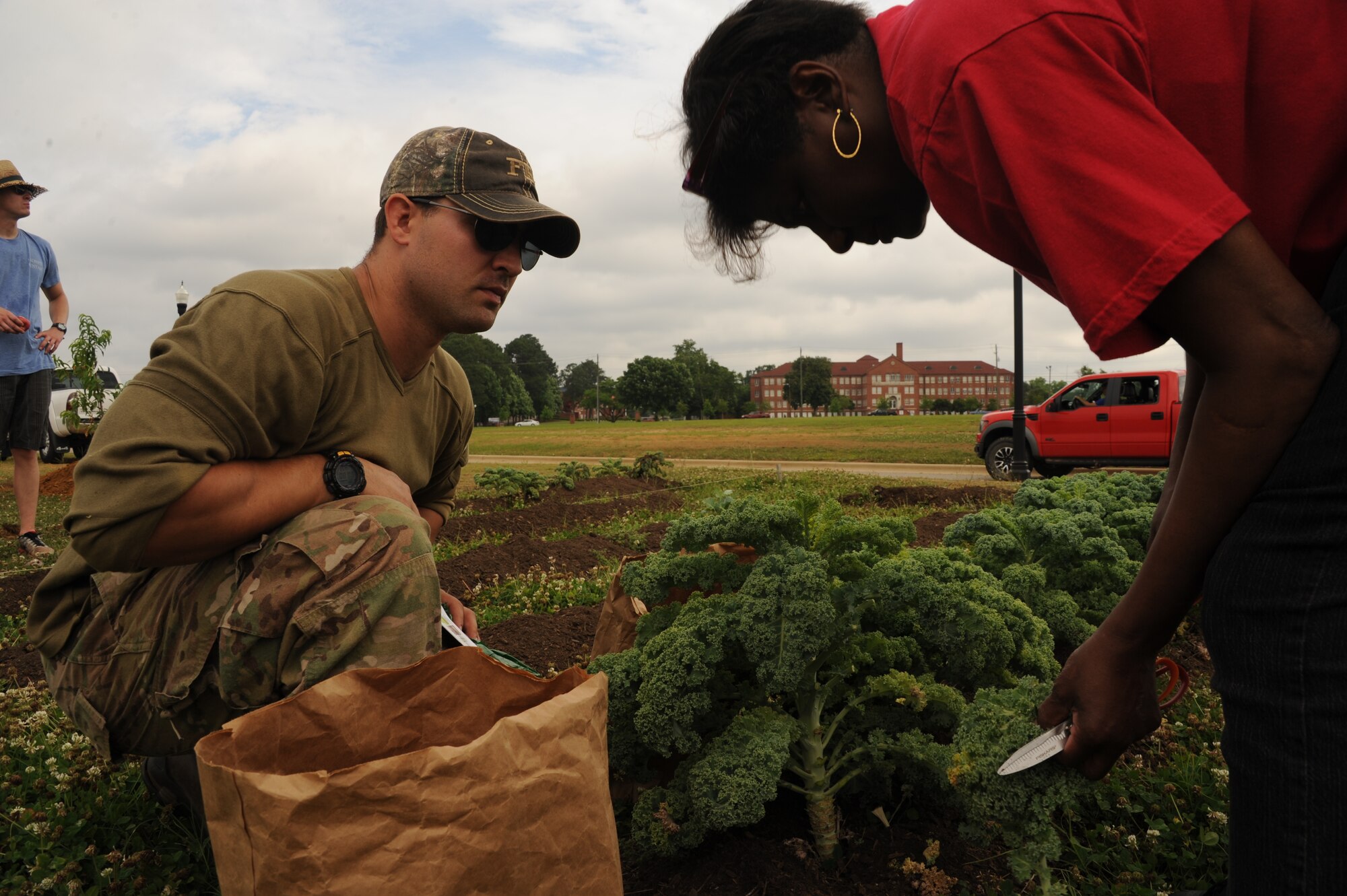 Capt. Scott Church, Squadron Officer School flight commander, left, and Dianna Wilkerson, Carver High School culinary arts teacher, collect kale from Carver’s garden, May 16, 2014, Montgomery, Alabama. Church and approximately 25 SOS students not only raised money for gardening supplies, but extended a hand in the construction of the garden for Caver’s culinary arts program. (U.S. Air Force photo by Airman 1st Class Alexa Culbert/Cleared)