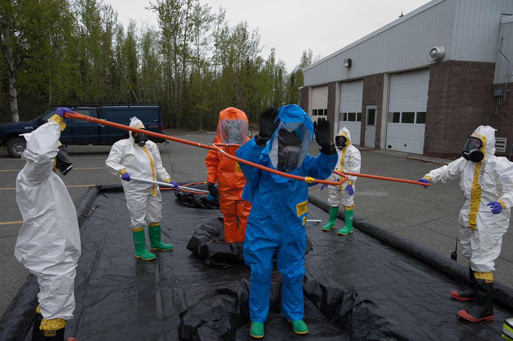 Senior Airman Matthew Castellanos, blue, and Air National Guard Air National Guard Staff Sgt. James Mainolfi, orange, go through simulated decontamination in their fully encapsulated chemical suits during Integrated Base Emergency Response Training on Joint Base Elmendorf-Richardson, Alaska, May 14, 2015. Castellanos is a 773d Civil Engineer Squadron bio-environmental engineering technician and a native of Wescovena, Calif. Mainolfi is a 176th Medical Group bio-environmental engineering technician and a native of Rutland, Vermont. (U.S. Air Force photo/Tech. Sgt. Robert Barnett)