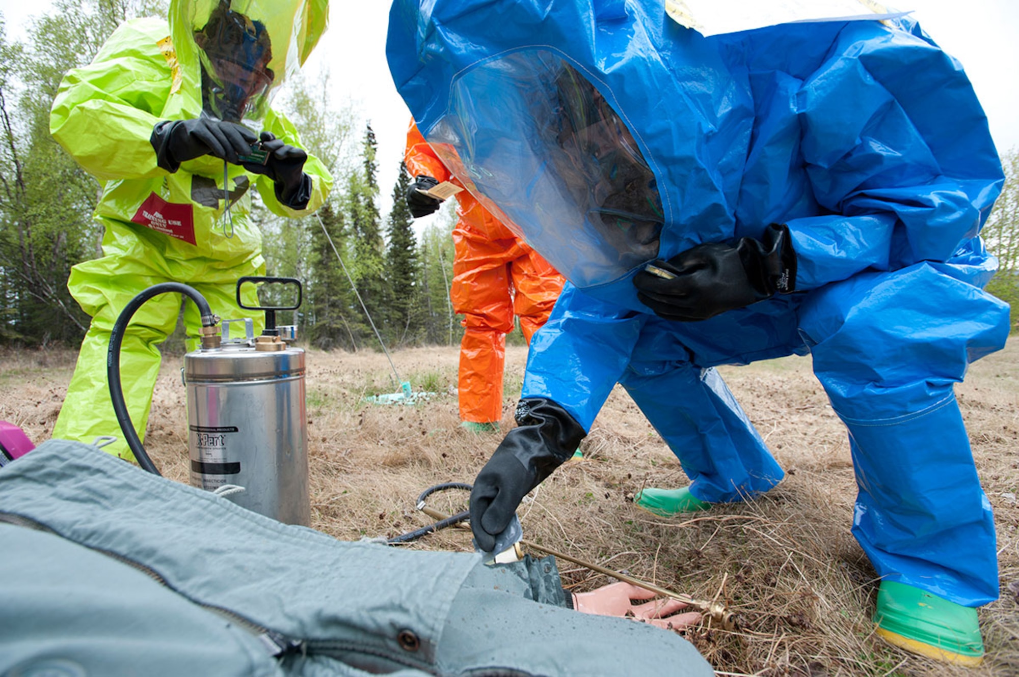 Senior Airman Matthew Castellanos, far right, dips M-8 and M-9 paper into chemicals on a simulated body to determine what the chemicals are during Integrated Base Emergency Response Training on Joint Base Elmendorf-Richardson, Alaska, May 14, 2015. The annual training is mandated by the Pacific Air Forces to provide more in-depth specialty training than normal exercises. (U.S. Air Force photo/Tech. Sgt. Robert Barnett)