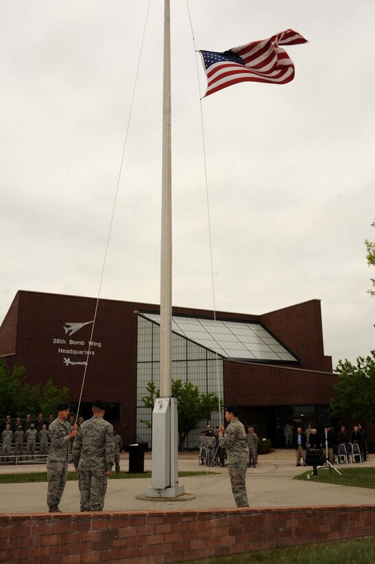 Members of the 28th Security Forces Squadron prepare to lower the flag during a National Police Week retreat ceremony at Ellsworth Air Force Base, S.D., May 14, 2015. National Police Week is an observance in the United States which pays tribute to local, state and federal law enforcement officers. (U.S. Air Force photo by Senior Airman Hailey R. Staker/Released)
