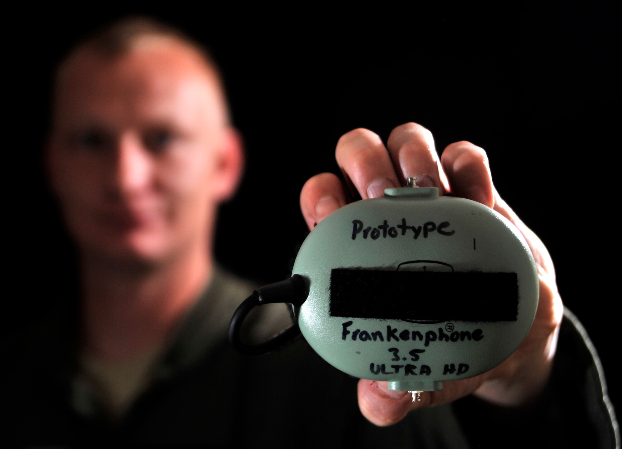 SSgt. Marion, 42nd Attack Squadron sensor operator, poses for a photo with his invention, the Frankenphone 3.5 Ultra High Definition March 24, 2015, at Creech Air Force Base, Nevada. The Frankenphone gets its name because of the way it’s patched together from decommissioned pieces of equipment. It’s a simple design but the Frankenphone improves air-to-ground communications by putting the aircrew and Joint Terminal Attack Controllers on a party line mitigating the need to repeat messages numerous times and improving communications clarity. This in turn allows operators to seamlessly execute the mission and save lives. (U.S. Air Force photo by Airman 1st Class Christian Clausen/Released)