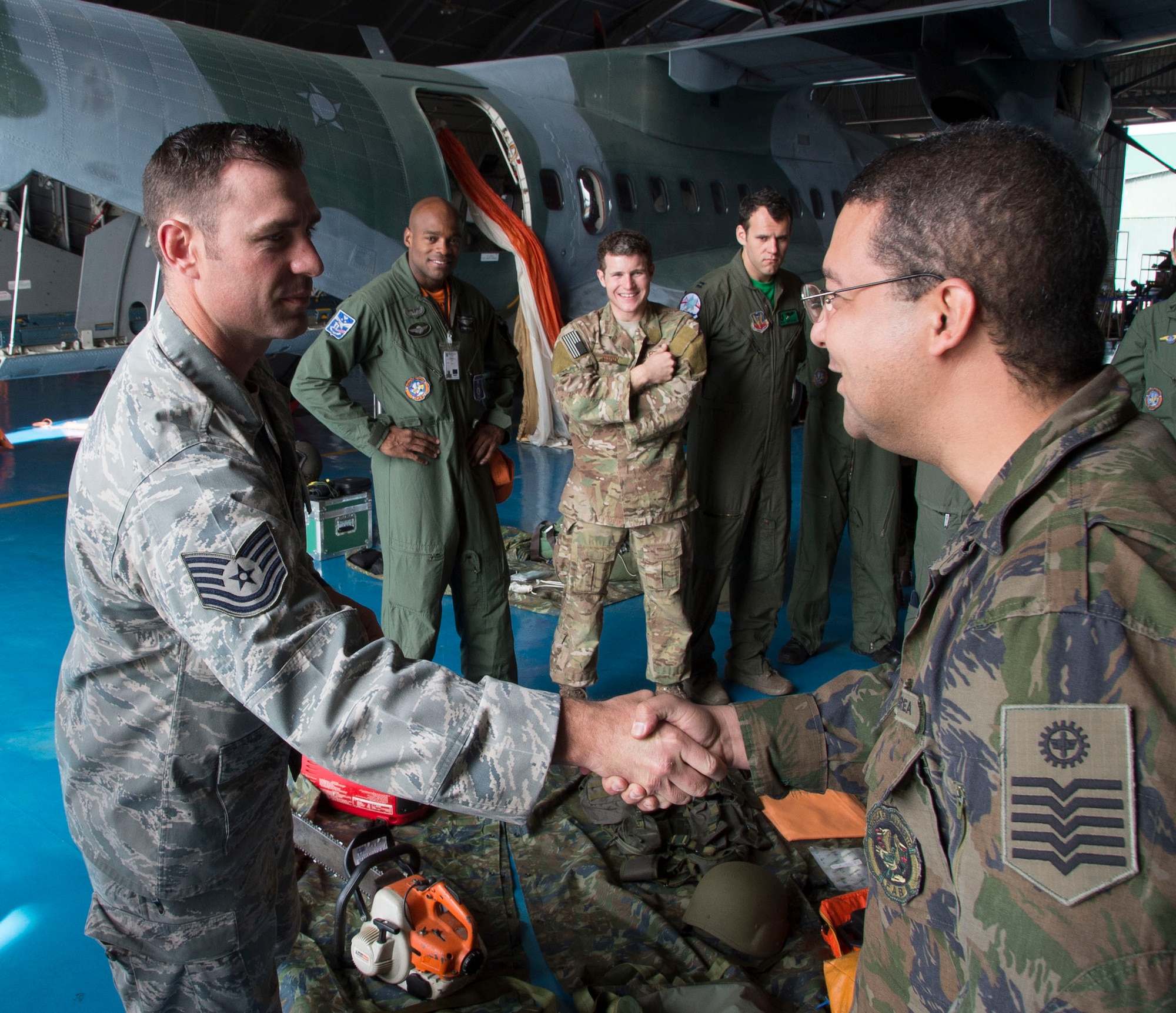 Tech Sgt. Daniel Foret, 571st Mobility Support Advisory Squadron survival, evasion, resistance and escape specialists, shakes hands with a member of the Brazilian air force’s air crew flight equipment section after a demonstration on their capabilities, May 15, 2015 in Campo Grande, Brazil. Members of AFE are responsible for ensuring the equipment assigned to air crews is properly maintained. (U.S. Air Force photo by Staff Sgt. Adam Grant/Released)
