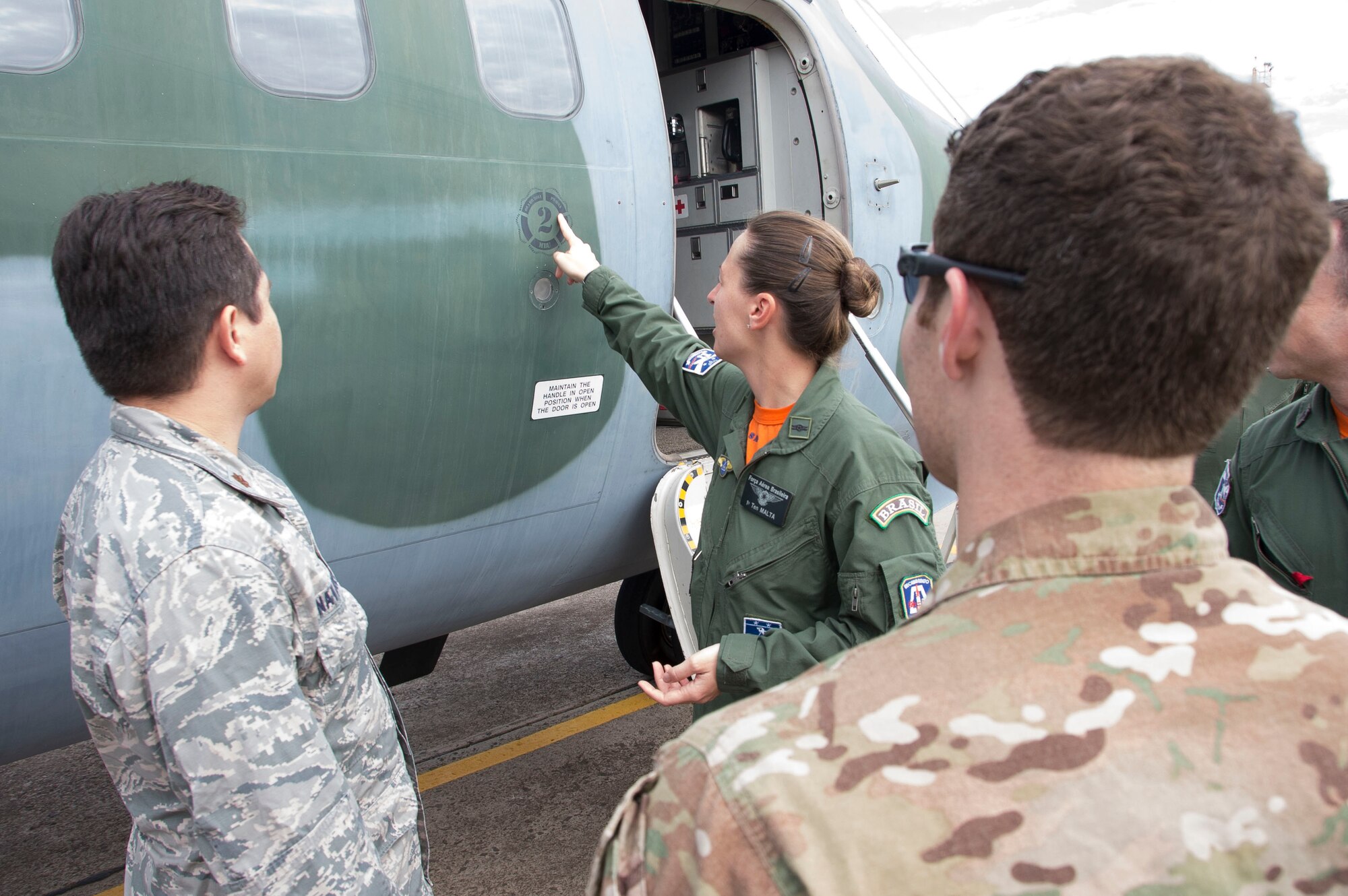 A member of the Brazilian air force points to a path located on the side of a C-105 Amazonas during a week-long exchange focused on enhancing the Search and Rescue capabilities of both the Unites States Air Force and the Brazilian air force, May 15, 2015 in Campo Grande, Brazil. The patch signifies the aircraft it’s placed on was involved in a SAR mission and the patient rescued was survived. (U.S. Air Force photo by Staff Sgt. Adam Grant/Released)