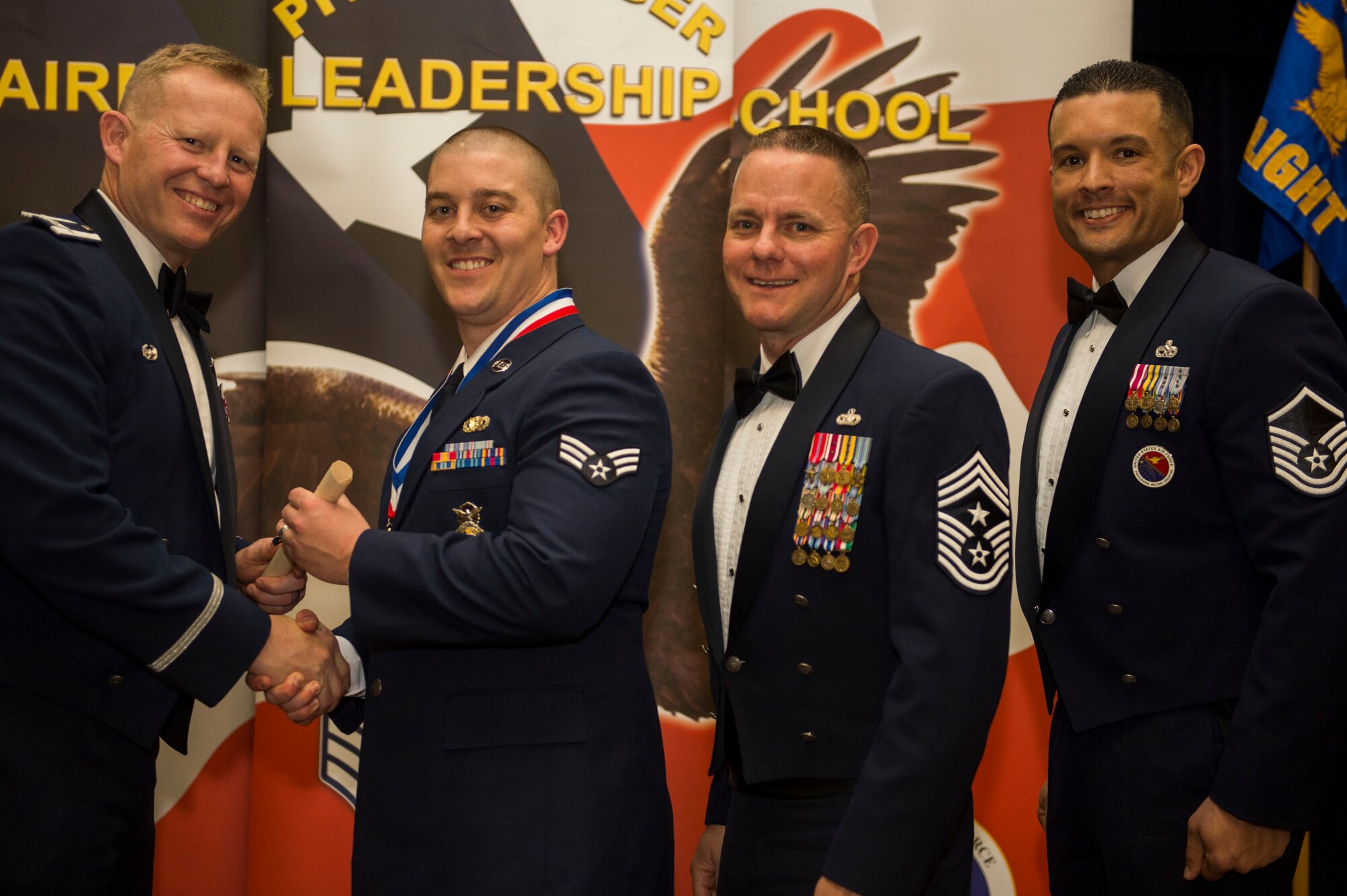 U.S. Air Force Col. Joe McFall, 52nd Fighter Wing commander, left, and U.S. Air Force Chief Master Sgt. Brian Gates, 52nd FW command chief, center right, and U.S. Air Force Master Sgt. Roberto Oregon, Pitsenbarger Airman Leadership School commandant, right, congratulate U.S. Air Force Senior Airman Brandon Stone, 701st Munitions Support Squadron and John L. Levitow Award recipient, center left, during the Pitsenbarger ALS class 15-D graduation ceremony at Club Eifel at Spangdahlem, Germany, May 14, 2015.  The Levitow award is presented to the student who demonstrated the most outstanding leadership and scholastic qualities based on academic performance and assignment of points by peers and instructors. (U.S. Air Force photo by Airman 1st Class Timothy Kim/Released)