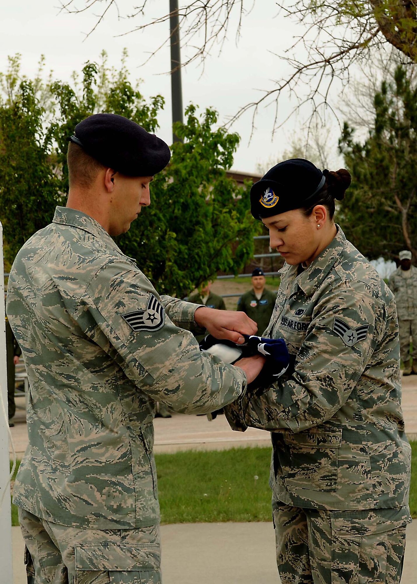 Staff Sgt. Matthew Eichner and Senior Airman Amaris Serrano, 28th Security Forces Squadron base defense operations center controllers, fold the American flag in honor of fallen security forces personnel and police officers during a National Police Week retreat ceremony at Ellsworth Air Force Base, S.D., May 14, 2015. Since 1791, more than 19,000 U.S. police officers have passed away while serving their communities. (U.S. Air Force photo by Senior Airman Hailey R. Staker/Released)  