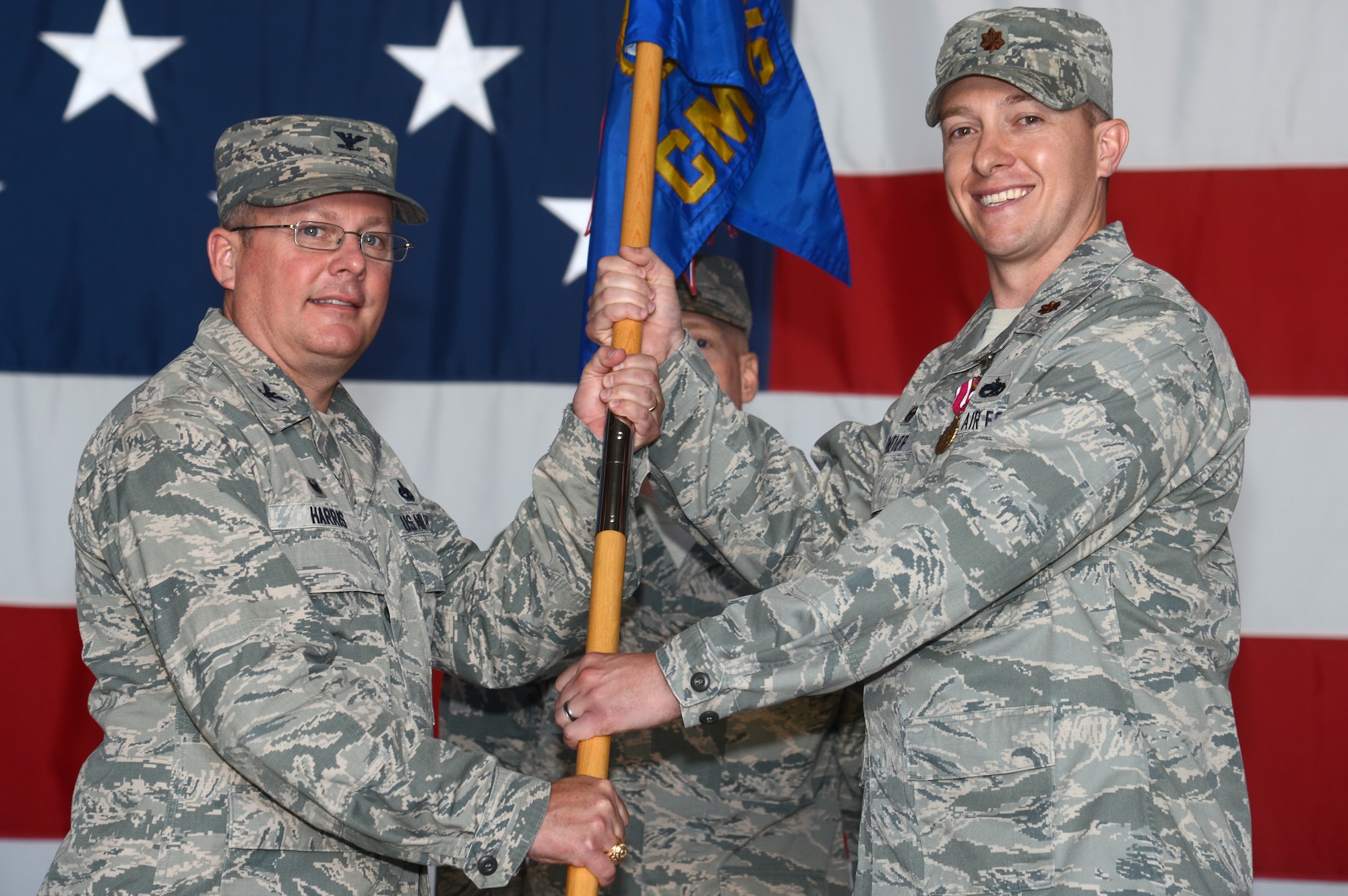 U.S. Air Force Maj. Jason Kneuer, 20th Component Maintenance Squadron outgoing commander, passes the guidon to Col. Bryan Harris, 20th Maintenance Group commander, while relinquishing command during a change of command ceremony at Shaw Air Force Base, S.C., May 18, 2015. The traditional change of command ceremony dates back to 18th century Prussia during the reign of Frederick the Great. (U.S. Air Force photo by Senior Airman Jonathan Bass/Released)