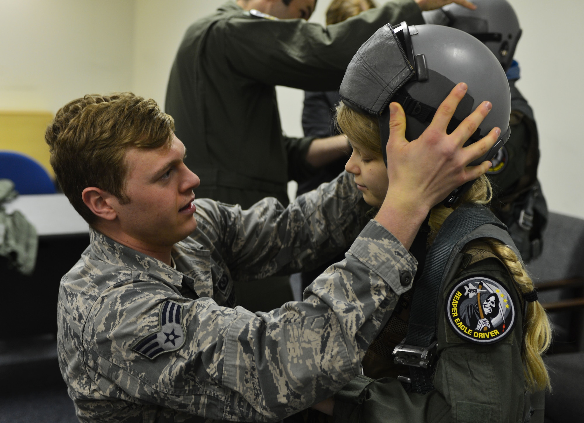 U.S. Air Force Senior Airman Justin Bishop, 871st Air Expeditionary Squadron aircrew flight equipment section, fits Arna Tryggvadóttir with a helmet during the Pilot for a Day program at Keflavik International Airport, Iceland, May 13, 2015.The 871st AES hosted two children, who were fitted with aircrew flight equipment as part of the day-long program.(U.S. Air Force photo by 2nd Lt. Meredith Mulvihill/Released)