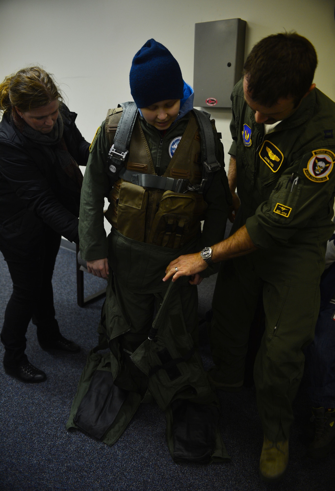 U.S. Air Force Capt. Jason Ford, 871st Air Expeditionary Squadron F-15C Eagle fighter aircraft pilot, and Aðalheiður Þorsteinsdóttir, Gunnar Guðlaugsson's mother, help Guðlaugsson don flight equipment during the Pilot for a Day program at Keflavik International Airport, Iceland, May 13, 2015. The 871st AES hosted two children as part of the program,who were fitted with aircrew flight equipment and introduced to what a day in the life of a U.S. Air Force pilot is like. (U.S. Air Force photo by 2nd Lt. Meredith Mulvihill/Released)
