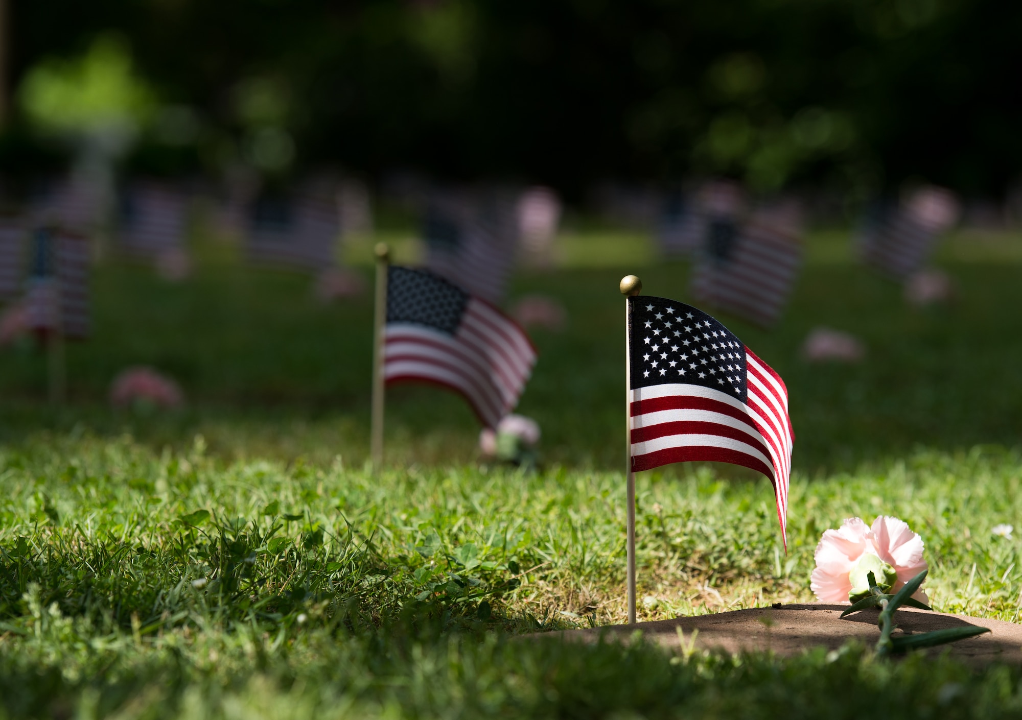 U.S. flags are placed next to grave stones during the Kindergraves memorial service May 16, 2015, in Kaiserslautern, Germany. Children buried here were no more than 12 months old during 1952 to 1971, most died of various childhood diseases or birth complications. Each spring floral wreaths are placed at the front monument along with a candle lighting ceremony in memory of the children, as well as American flags placed at each grave marker. (U.S. Air Force photo/Senior Airman Jonathan Stefanko)