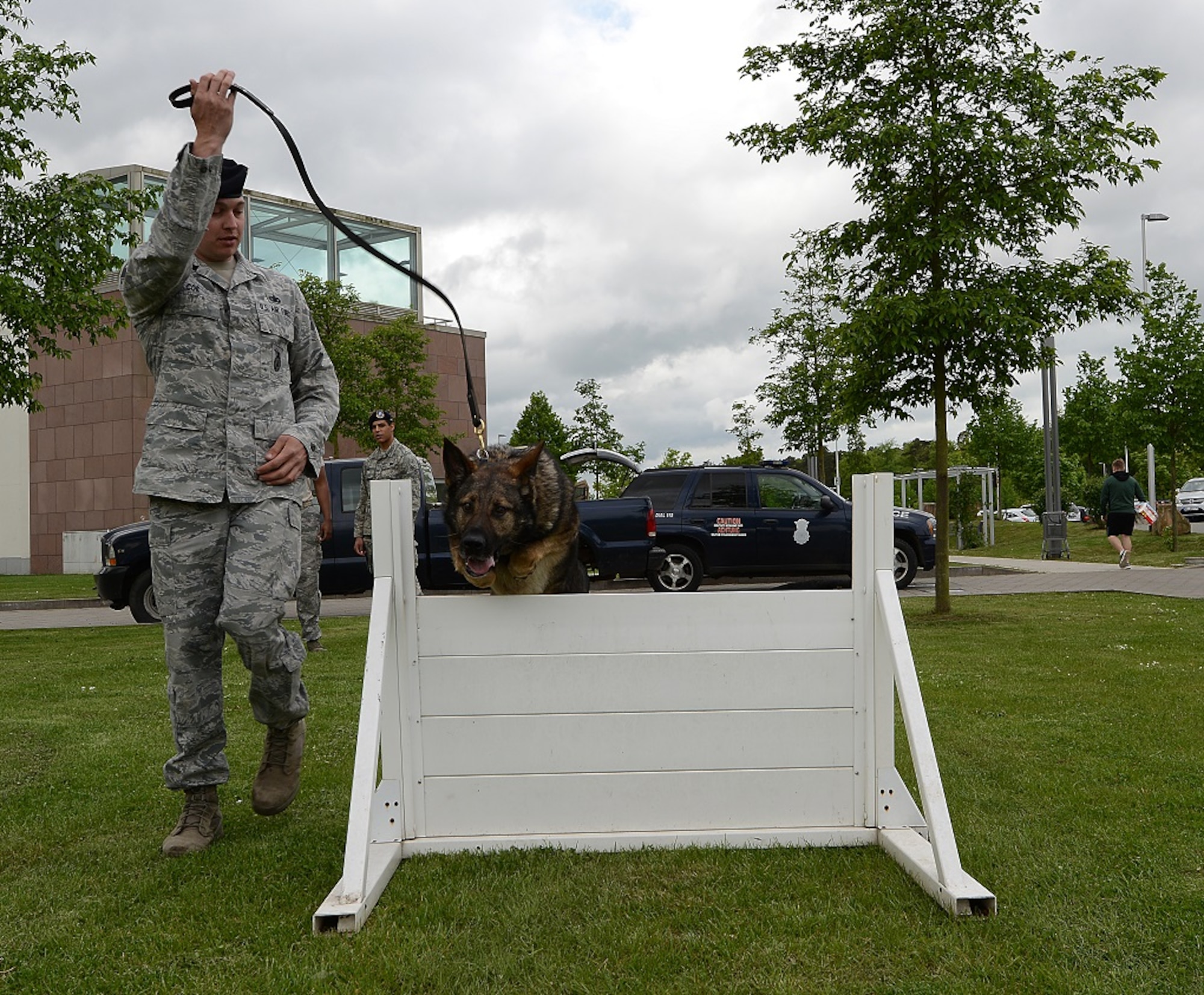 Staff Sgt. Chad Coe, 86th Security Forces Squadron military working dog handler, leads Charone, 86th SFS MWD, over a hurdle as part of a MWD demonstration May 9, 2015, at Ramstein Air Base, Germany. The demonstration was part of a display held at the Kaiserslautern Military Community Center in honor of National Police Week. (U.S. Air Force photo/Airman 1st Class Tryphena Mayhugh)