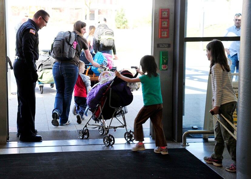 Carl Bryerton, U.S. Army Customs Europe customs inspector, opens a door for a family at the Ramstein Passenger Terminal April 14, 2015, at Ramstein Air Base, Germany. Customs members at the terminal have many jobs such as checking cargo, directing traffic and safeguarding the environment and people. (U.S. Air Force photo/Airman 1st Class Larissa Greatwood)