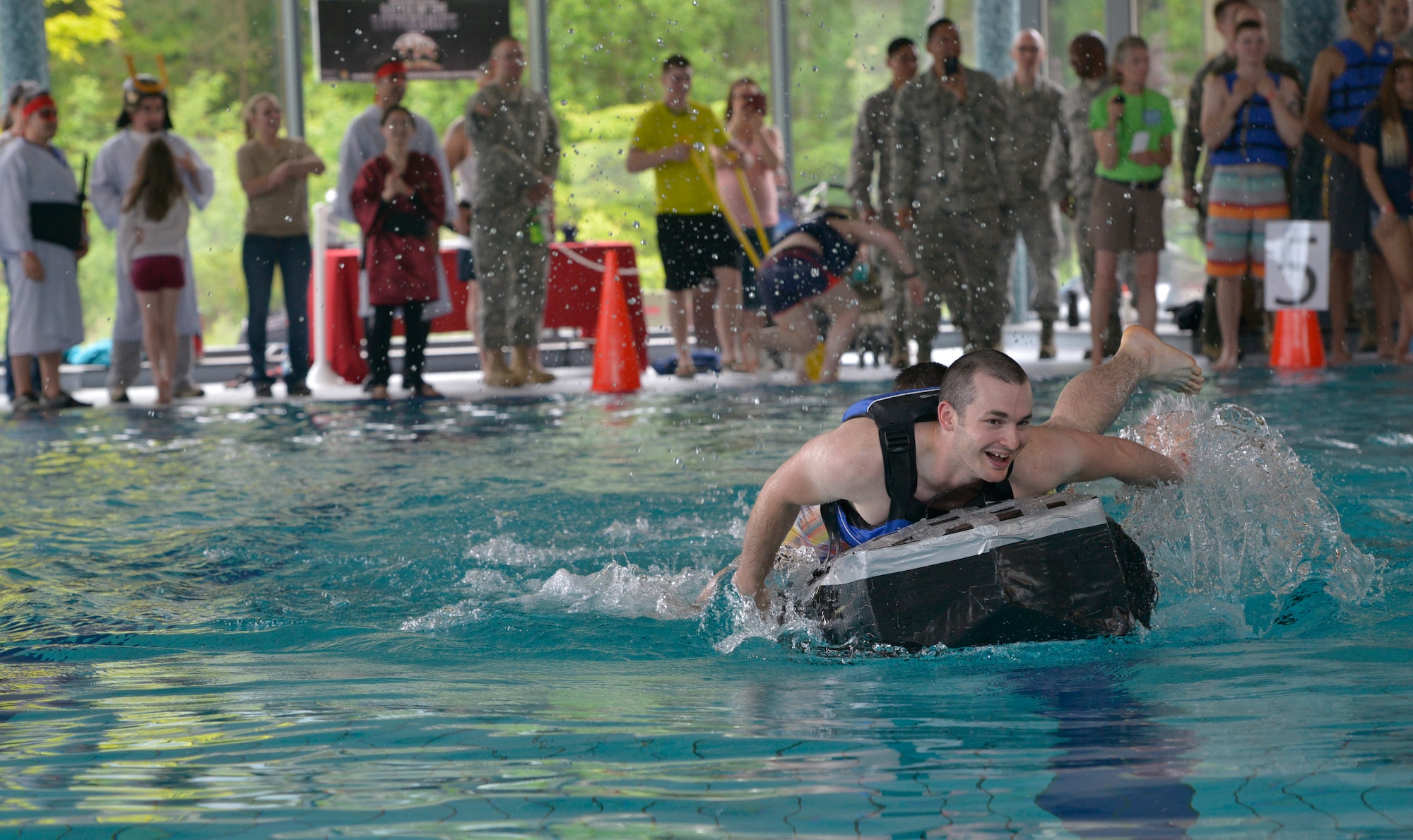 A participant pedals his boat after flipping it over at the start of a race during the Battle of the Battleships competition May 15, 2015, at Ramstein Air Base, Germany. The competition began with races, where several teams were tasked to pedal their boats to one side of the pool and back as quickly as possible. (U.S. Air Force photo by Airman 1st Class Lane T. Plummer/Released)