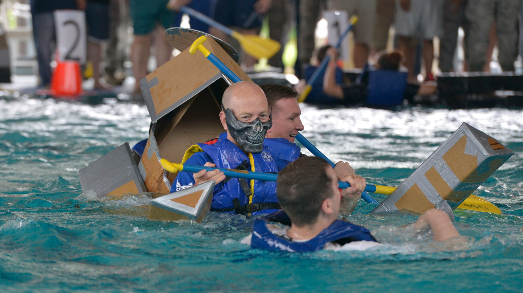 Three participants sink in their collapsing boat during the Battle of the Battleships competition May 15, 2015, at Ramstein Air Base, Germany. Teams were tasked to bring their own boats to use in the competition built from only duct tape and cardboard. (U.S. Air Force photo by Airman 1st Class Lane T. Plummer/Released)