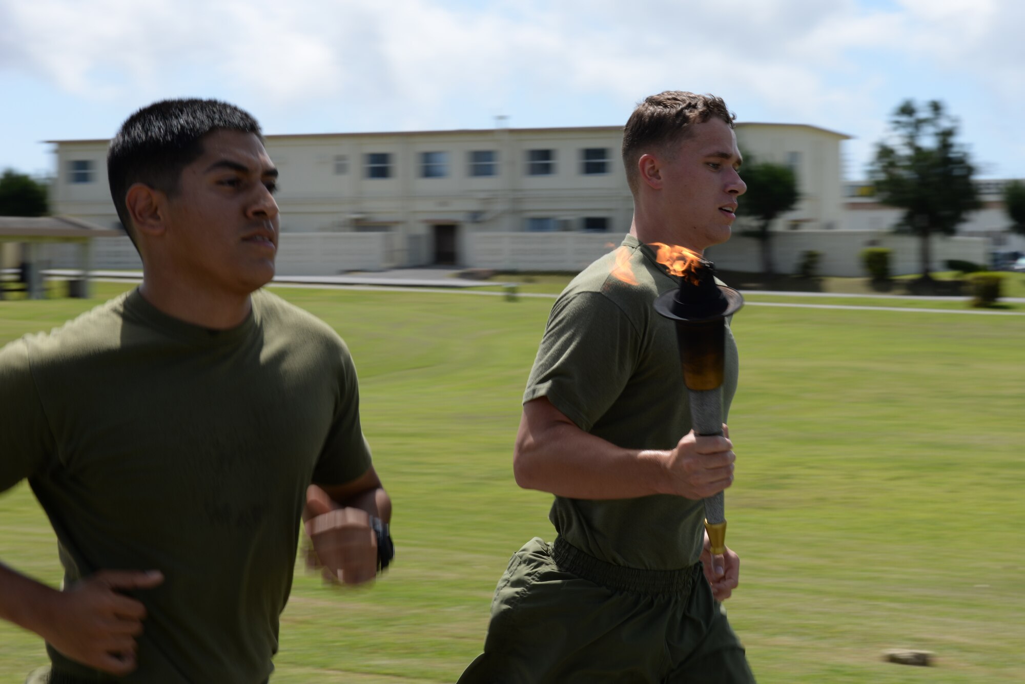 U.S. Marine Corps Lance Cpls. Mathew Mena and Alec Toney, 3rd Law Enforcement Battalion military policemen, carry a torch as they run around Marek Field Park for the National Police Week 24-hour vigil run on Kadena Air Base, Japan, May 14, 2015. The torch is carried while burning for 24 hours by multiple military policemen and then ran to the site of the memorial service. (U.S. Air Force photo by Senior Airman Omari Bernard)