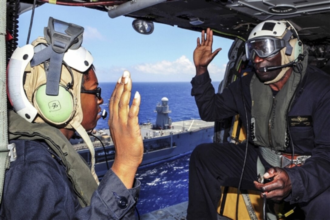 U.S. Navy Petty Officer 2nd Class Icerine Wyngarde, left, takes the oath of re-enlistment from U.S. Navy Cmdr. Hezekiah Natta, communications officer for U.S. 7th Fleet flagship USS Blue Ridge, in an MH-60S Seahawk helicopter in the Philippine Sea, May 15, 2015. The Blue Ridge is supporting the 7th Fleet mission to strengthen and foster relationships within the Indo-Asia-Pacific region.