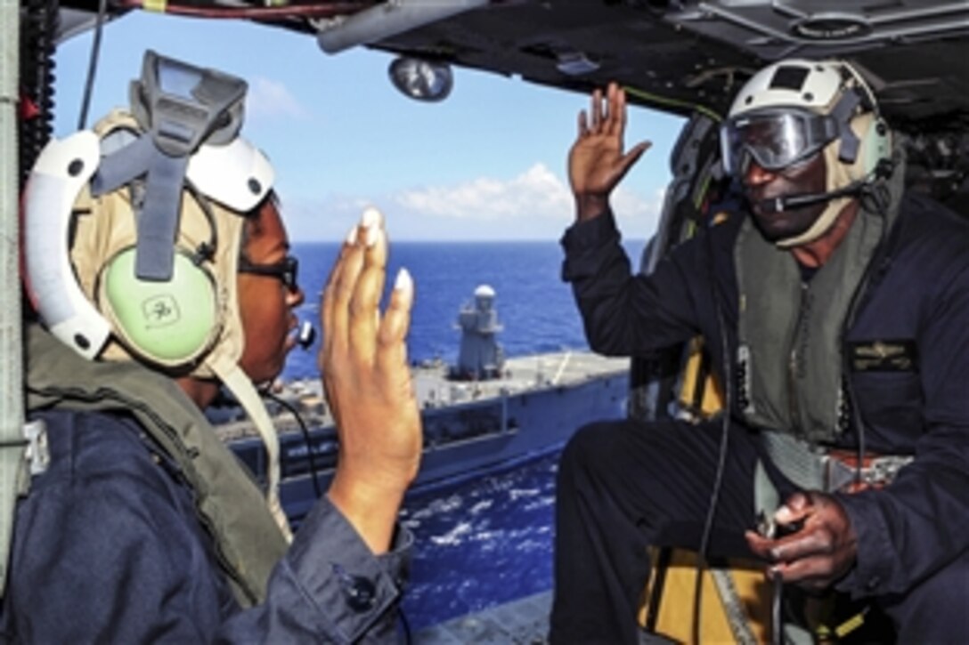 U.S. Navy Petty Officer 2nd Class Icerine Wyngarde, left, takes the oath of re-enlistment from U.S. Navy Cmdr. Hezekiah Natta, communications officer for U.S. 7th Fleet flagship USS Blue Ridge, in an MH-60S Seahawk helicopter in the Philippine Sea, May 15, 2015. The Blue Ridge is supporting the 7th Fleet mission to strengthen and foster relationships within the Indo-Asia-Pacific region.