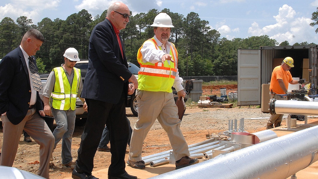 Assistant Secretary of the Navy, the Honorable Dennis V. McGinn (center), Energy, Installations and Environment, tours the ground source heat pump project area with Charles W. Hammock Jr., vice president, Andrews, Hammock and Powell, INC., during his visit to Marine Corps Logistics Base Albany, Georgia, May 19. The project is a borehole thermal energy storage system which is a state-of-the-art ground source heat pump system for heating and cooling Building 3700, the Marine Corps Logistics Command headquarters building.  