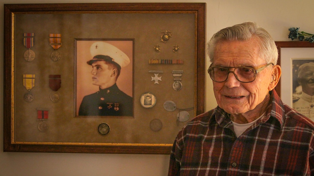 Retired U.S. Marine Staff Sgt. Robert A. Henderson, 95, a Pearl Harbor survivor, poses next to his medals and a photo of himself from the era, Feb. 21, 2015. "Living this long is no accident," he explained. "It takes work." Henderson served 51 months in combat during WWII, culminating at the Battle of Okinawa. "I was in the first and last battles of the war." (Photo by Ken Scar)