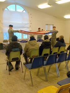 Members of the Alaska National Guard Military Funeral Honors Team fold the American flag during a ceremony honoring Alaska Territorial Guardmembers who never received military funeral honors. The Guardmembers travelled to Akiachak to present the flag to family members and honor those who served their state and country.