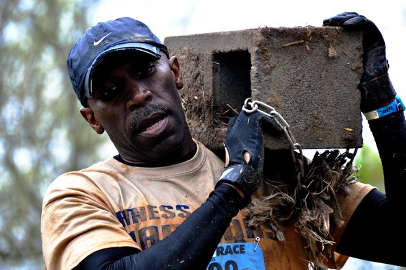 Senior Master Sgt. Eric Jones, 94th Logistics Readiness Squadron, carries a masonry brick down a hill during the Georgia Spring 2015 Savage Race in Dallas, Ga., April 18, 2015. The Savage Race is an Air Force Reserve sponsored obstacle course that challenges participants in more than 20 different trials over the course of five miles. (U.S. Air Force photo/Senior Airman Daniel Phelps)