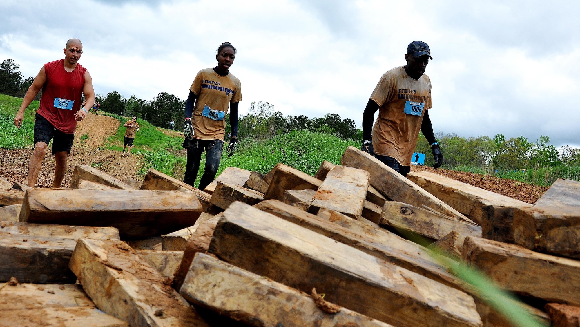 Staff Sgt. Luis Pluguez, 94th Aeromedical Staging Squadron, Senior Master Sgt. Eric Jones, 94th Logistics Readiness Squadron, and Jones’ daughter Erica grab blocks of wood to carry during the Georgia Spring 2015 Savage Race in Dallas, Ga., April 18, 2015. The Savage Race is an Air Force Reserve sponsored obstacle course that challenges participants in more than 20 different trials over the course of five miles. (U.S. Air Force photo/Senior Airman Daniel Phelps)