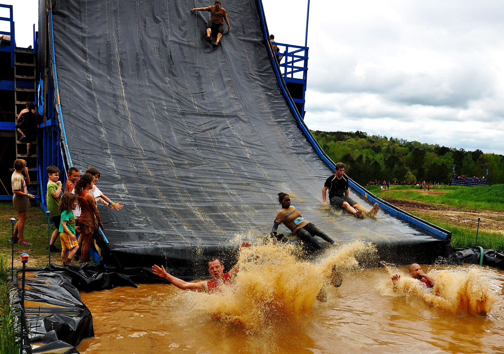 Members of Dobbins Air Reserve Base slide into a pool of water after making it to the top of the Colossus during the Georgia Spring 2015 Savage Race in Dallas, Ga., April 18, 2015. The Colossus was a giant 43-foot wall and one of the hardest obstacles in the course. Adding to the difficulty of it being one of the final obstacles, runners had to sprint up the barrier after they’d already sledged through more than four miles in the mud, before grabbing a rope. They would then pull themselves up to the top of the fortification. The Savage Race is an Air Force Reserve sponsored obstacle course that challenges participants in more than 20 different trials over the course of five miles. (U.S. Air Force photo/Senior Airman Daniel Phelps)