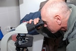 Army Maj. Loren Adams, a New Liberty, Iowa, resident and a veterinarian with the Iowa National Guard Agribusiness Development Team, examines an anthrax slide through a microscope in the Central Veterinary Research and Diagnostics Lab in Kabul City here during a tour Dec. 28. The tour gave a group of Army vets a better understanding of the lab’s capabilities which they will pass on to the Afghan veterinarians they work with, in their respective provinces.
