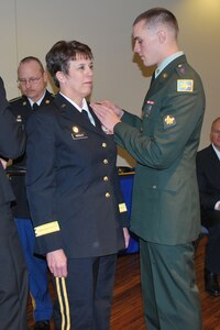 Army Spc. Blayne Wright, 133rd Engineer Company, Wyoming National Guard, places the rank of brigadier general on his mother, Brig. Gen. Kathy Wright, during her promotion ceremony, Jan. 5, 2011, in Cheyenne, Wyo. The general is the first woman to obtain the rank of brigadier general in the Wyoming Army National Guard. She serves as Wyoming's assistant adjutant general - Army, overseeing all units and soldiers in the Wyoming Army National Guard.