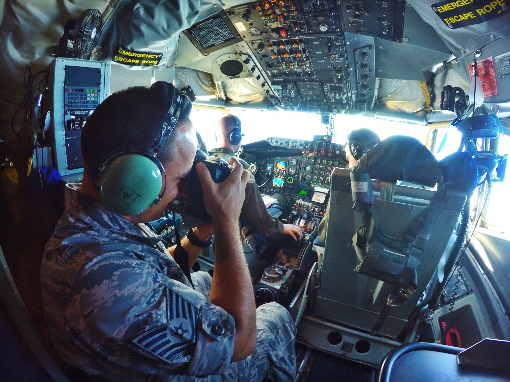 Tech Sgt. Aaron Oelrich, a photojournalist from 15th Wing public affairs, captures a picture of Capt. Ryan Miller and Maj. Dan Allen, pilot evaluators for the 96th Air Refueling Squadron, on Joint Base Pearl Harbor-Hickam, Hawaii, May 19, 2015. Members of the public affairs office were on board the KC-135R Stratotanker flight to document aerial refueling operations for six F-22 Raptors from the Hawaiian Raptors. (U.S. Air Force photo by 2nd Lt. Kaitlin Daddona/Released)