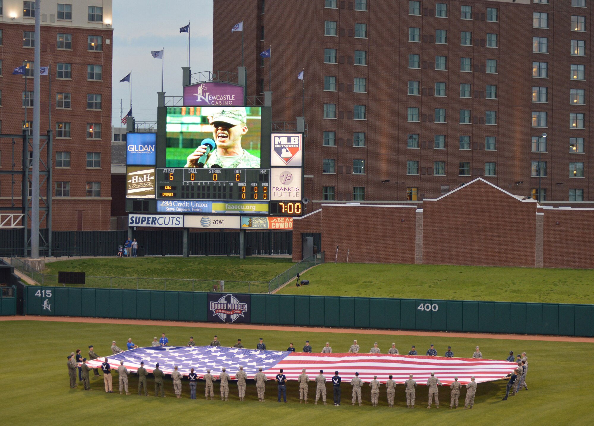 Airmen and Sailors from Tinker, along with several Air Force recruits, display the colors in centerfield at the Chickasaw Bricktown Ballpark to open Military Appreciation Night May 16.  Pictured on the Jumbotron is Staff Sgt. Daniel Jordan, who sang the national anthem. (Air Force photo by April McDonald/Released)